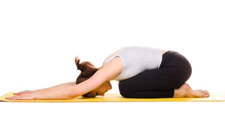 young woman practising yoga exercises on yellow mat isolated on white backgroundの写真素材