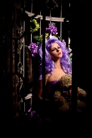 dreaming anime young woman with makeup in purple wig with soft toy in summerhouseの写真素材