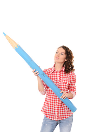 young pretty woman with wavy hair in checkered red shirt with big blue pencil isolated on white backgroundの写真素材