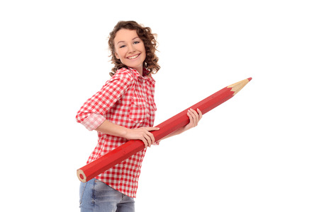 smiling young attractive woman with wavy hair in checkered shirt with giant red pencil isolated on white backgroundの写真素材