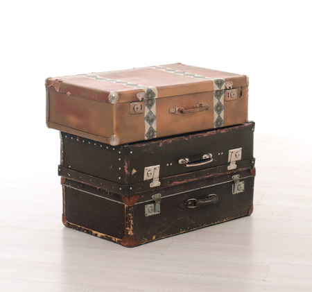 stack of three brown retro suitcases on floor on white studio backgroundの写真素材