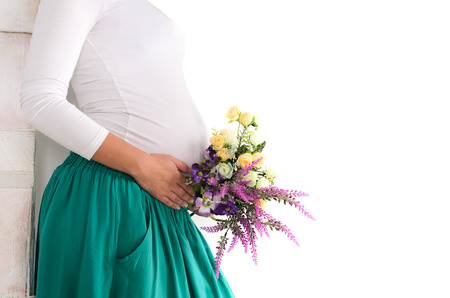 pregnant belly with flowers in a green skirt and a white jumperの写真素材