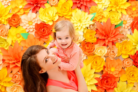 daughter at the hands of the mother against the backdrop of colorful flowers made of paperの写真素材
