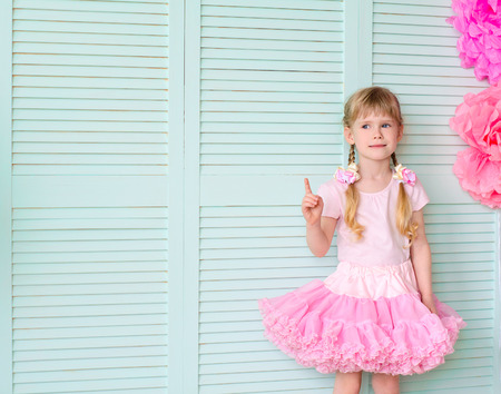 Beautiful girl with pigtails, wearing a skirt tutu, against a light green wallの写真素材