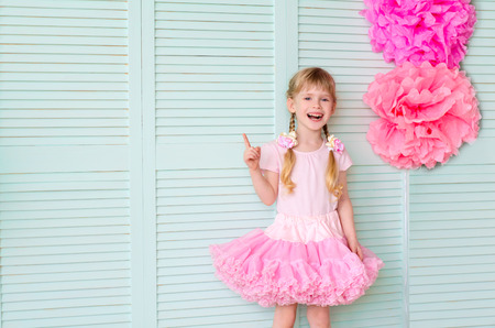 Beautiful girl with pigtails, wearing a skirt tutu, against a light green wallの写真素材