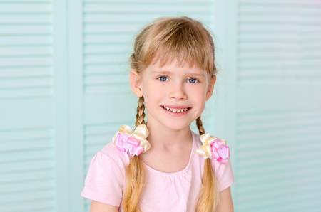 Beautiful smiling girl with pigtails, on a background of bright greenの写真素材