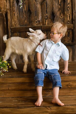 boy sits on wooden steps of porch, and gently communicates with newborn kidの写真素材