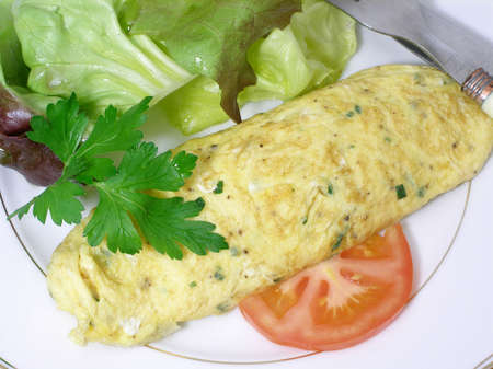 Wrapped omelet stuffed with chopped chives, served with red lettuce leavesの写真素材