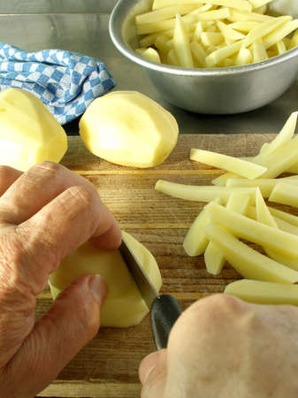 Chef's hands cutting french fries on a wooden cutting boardの写真素材