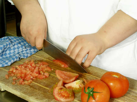 Chef is dicing tomatoes on the cutting boardの写真素材