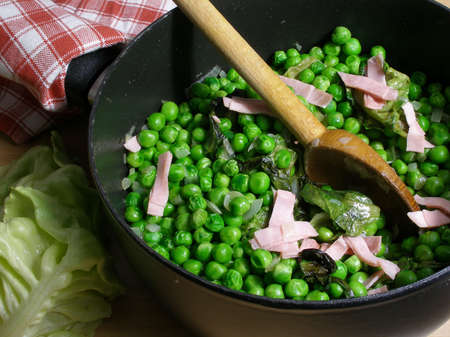 Garden peas cooked with lettuce and ham in a saucepanの写真素材