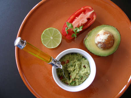 Guacamole presented with tomato on an earthware plateの写真素材