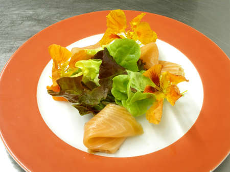 A plate of smoked salmon green leaves and nasturtiumの写真素材