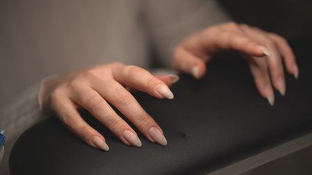 a girl at a session with a manicure master is waiting for the master to start the next procedureの写真素材