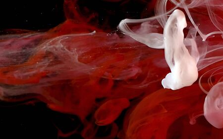 Red and white watercolor ink in water on a black background. Colored space magic background.の写真素材