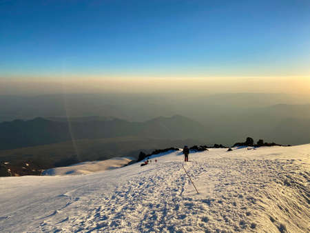 Mountain Elbrus. Climbers with backpacks and trekking poles walk along a snowy path. Beautiful...