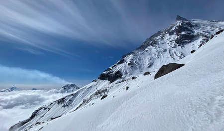 Volcano Stone. The Bezymyanny volcano is smoking in the background. View above the clouds from a...