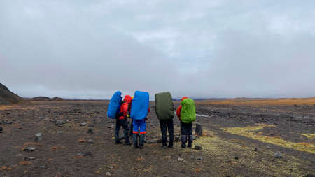 Group of tourists with large backpacks and trekking poles stand in a semicircle. Trekking in the Klyuchevskoy volcano park. Travel to the Kamchatka Peninsula.の写真素材