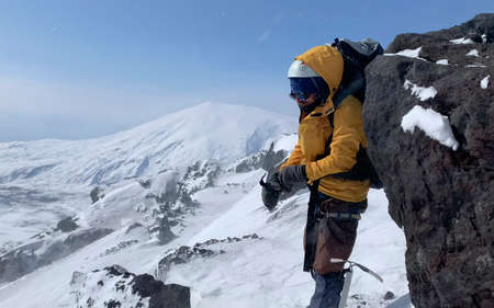 The climber puts on mittens on the way to the top. Mountain climbing. Trekking in the Klyuchevskoy...