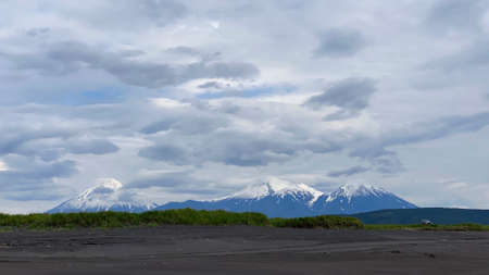 A breathtaking view of the volcanoes of Kamchatka. Khalaktyrsky beach with black volcanic sand. The amazing nature of Russia. Travel to the Kamchatka Peninsula.の写真素材