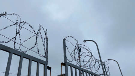 Fence with barbed wire against the gray sky. Protected area. Imprisonment concept.の写真素材