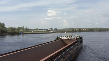 LENINGRAD REGION, RUSSIA - JUNE 1, 2021: An empty barge for transporting timber or sand floats down...