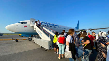 VLADIKAVKAZ, RUSSIA - JULY 20, 2021: People walk the ladder aboard the plane of Pobeda Airlines.