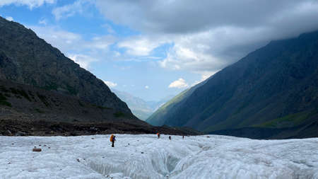A group of tourists walking along the Miley glacier. Impenetrable rocks, mountains and green hills...