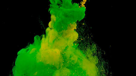 Green and yellow cloud of ink. Beautiful abstract background. Green and yellow watercolor ink in water on a black background. Waves and drops of green and yellow colors. Cosmic magic background.の写真素材