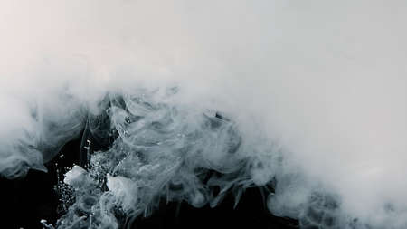 White watercolor ink in water on a black background. Beautiful abstract background.の写真素材