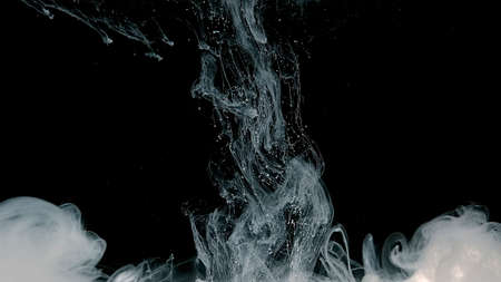 Waves and drops of white paints. White abstract background. White watercolor ink in water on a black background. Cosmic magic background. White cloud of ink.の写真素材