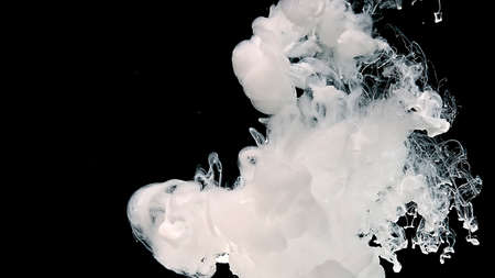 White cloud of ink on a black background. White watercolor paints in water. Meditative magic abstract background.の写真素材