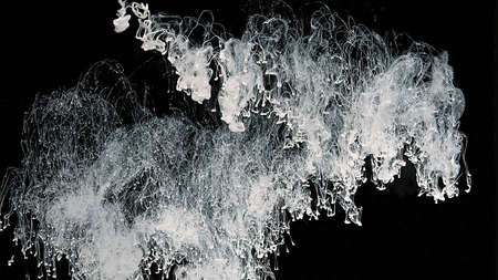 White cloud of ink on a black background. White watercolor paints in water. White watercolor ink in...