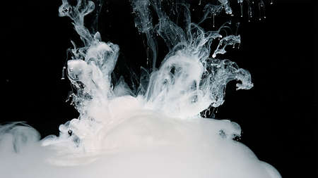 Waves of milky ink and splashes of white paints in the water. Black and white fantastic art. White watercolor ink in water on a black background. White abstract background.の写真素材