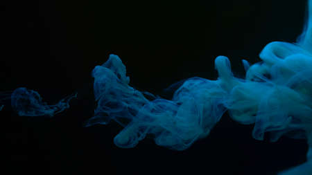 Blue-green watercolor paints in water on a black background. Chic wallpaper for your desktop. Creative hyptonic background. Blue-green cloud of ink on gray background. Beautiful abstract background.の写真素材