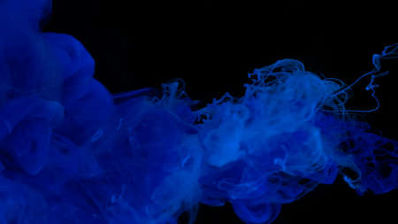 Blue watercolor paints in water on a black background. Awesome abstract background. Beautiful wallpaper for your desktop. Ultramarine cloud of ink on a black background. Drops of blue ultramarine ink in water.の写真素材