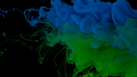 Colored cloud of ink on a black background. Drops of blue, green and light green ink in water. Blue, green and light green watercolor paints in water on a black background. Awesome abstract background. Beautiful wallpaper for your desktop.の写真素材