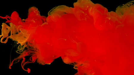 Orange ink droplets in water. Cosmic star background. Orange watercolor paints in water on a black...