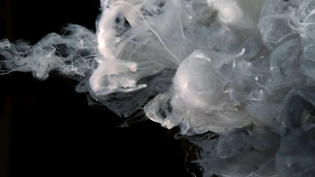 White cloud of ink on a black background. Drops of white and gray ink in water. Cosmic star...