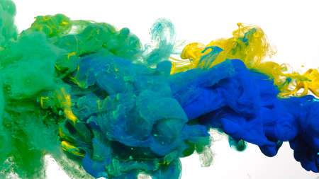 Blue, green and yellow watercolor ink in water on a white background. Beautiful abstract background. Acrylic paints are mixed in water. Colored cloud of ink on a white background.の写真素材