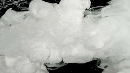 White cloud of ink, white smoke. Meditative background. White ink in water on a black background. Environmental pollution concept. Milky white awesome abstract background.の写真素材