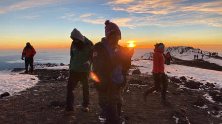 Kilimanjaro, Tanzania - January 1, 2022: A group of tourists on top of a mountain. Breathtaking sunrise in the mountains. Climbing Kilimanjaro.のeditorial素材