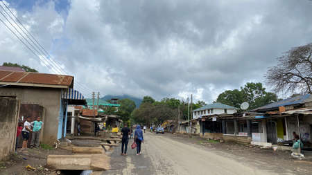 Kilimanjaro, Tanzania - December 26, 2021: On one of the streets of the city of Arusha. Poverty and slums. Green hills, roads and people. The amazing nature of Africa.のeditorial素材