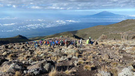Kilimanjaro, Tanzania - December 30, 2021: A group of tourists climb up the mountain. Climbing Kilimanjaro, Tanzania, Africa. beautiful mountain scenery. Mount Meru on the horizon.のeditorial素材