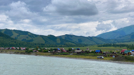 Russian village on the bank of the Katun River, Altai, Russia. Green wooded hills, ridges and mountains. View from the height of the Katun River. beautiful green valley. Calm natural background.の写真素材