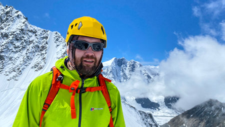 Tomsk Students Peak, Altai, Russia â€“ July 2, 2023: Portrait of a climber in a bright green...