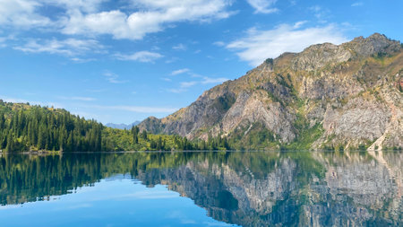 Sary Chelek mountain lake in Kyrgyzstan. Panorama of the summer landscape. Mountains, rocks and hills covered with green forests. The State Biosphere Reserve is a specially protected natural territory of Kyrgyzstan.の写真素材
