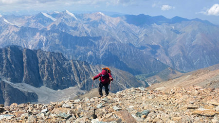 Active summer holidays. A tired lonely tourist with trekking poles climbs uphill. Ala Archa National...