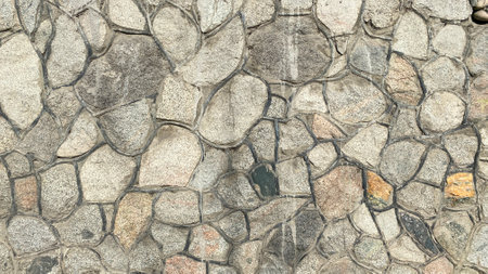 A wall of stones of different sizes and colors. Beautiful texture of stone masonry with veins....