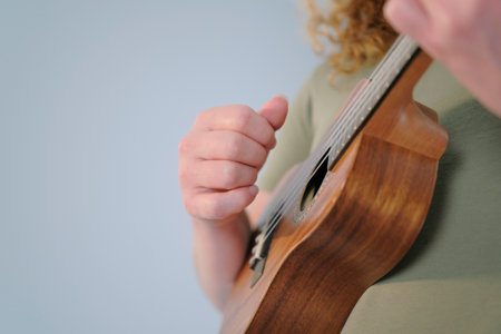 The guitarist plays the ukulele, close-up, focus on the hand. A man holds a ukulele in his hands and plays it. The concept of relaxation and enjoyment, as the musician is most likely strumming the strings and making musicの写真素材